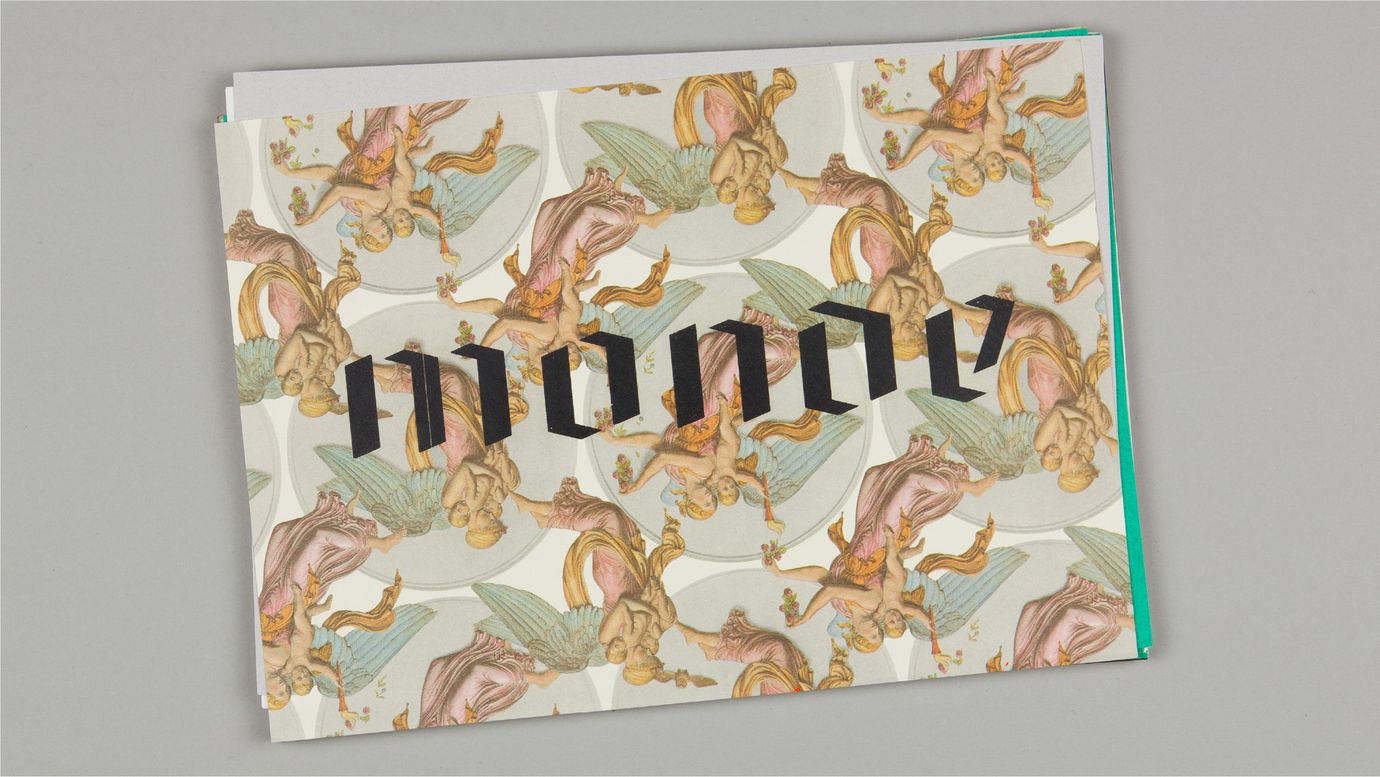 The word 'monde' in a simple gothic stencil font, screen-printed on a cheesy gift wrap with warm-colored angels holding candles.
